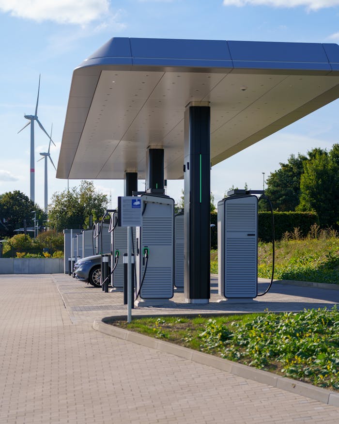 Electric car charging station with renewable energy wind turbines in a modern outdoor setting.